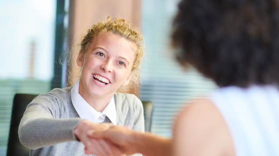 Smiling woman shaking hands with another woman