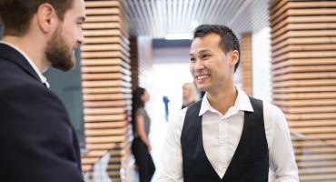 Man smiling at another man in a hall in an office