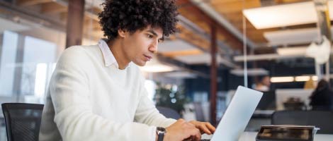 man sitting at desk typing on a laptop