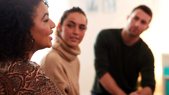 A diverse group of people, including two men and two women, sitting together and engaging in conversation.