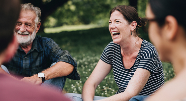 People talking and smiling in an outdoor setting, representing mental health resources.