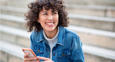 A young woman with curly hair smiling directly at the camera, representing the My Highmark app.
