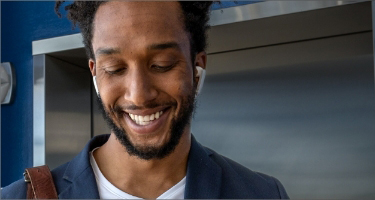 Smiling black man with earbuds in looking downward to show how the Highmark Because Life playlist is enjoyable. 