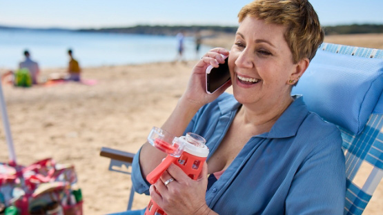 Woman at beach talking on mobile phone to show ease of contacting a registered RN covered by Highmark Blue Cross Blue Shield Delaware. 