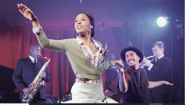 photo of a stage dancer with a band behind her