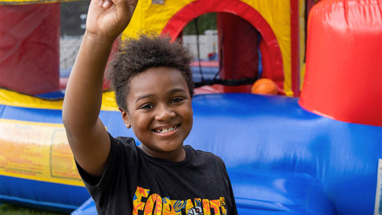 a child smiling in front of a bouncy house