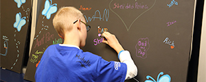 photo of a young man drawing on a chalkboard