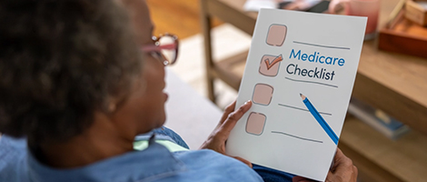 view over a woman's shoulder, she is holding the Medicare Checklist brochure