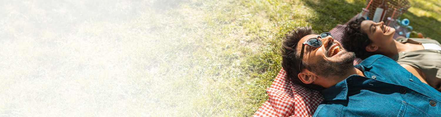 a man and women laying on the grass outside enjoying the sunshine