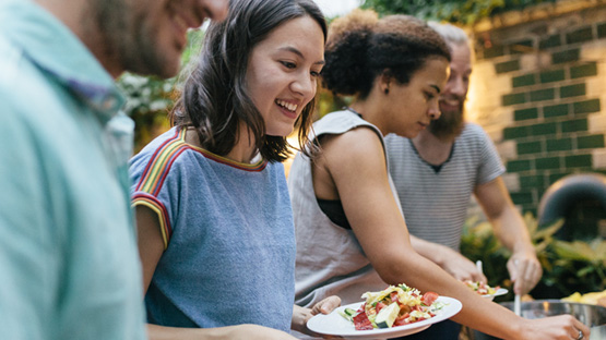 a group of friends serving themselves food at an outdoor party