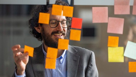 a young worker adding post its to a glass wall