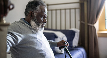 Older black man with cane considers high cost of chronic disease in the US.