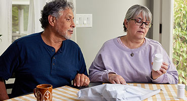 man and women checking their prescription drug bottle