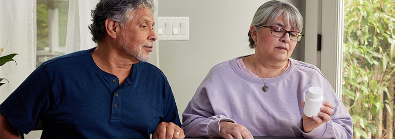 Middle aged man and women reviewing a prescription drug bottle.