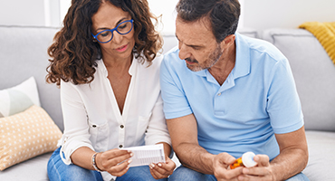 Middle aged man and women reviewing a prescription drug bottle and notes.