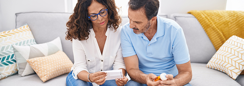 Middle aged man and women reviewing a prescription drug bottle and notes.