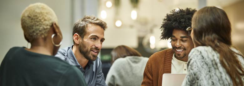 a diverse group of people sitting around a table chatting