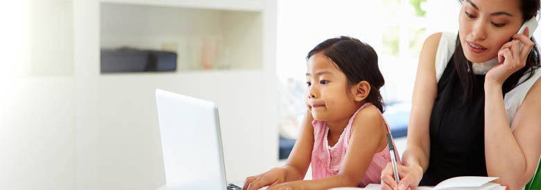 a little girl is on a laptop computer while the mother is busy working