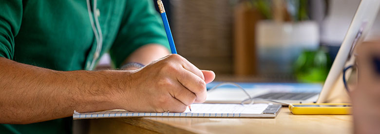 Two millennials, a young man and a young woman, meeting and taking notes a laptop computer in a shared workspace.