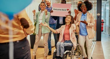 a women in a wheel chair celebrating with her co workers