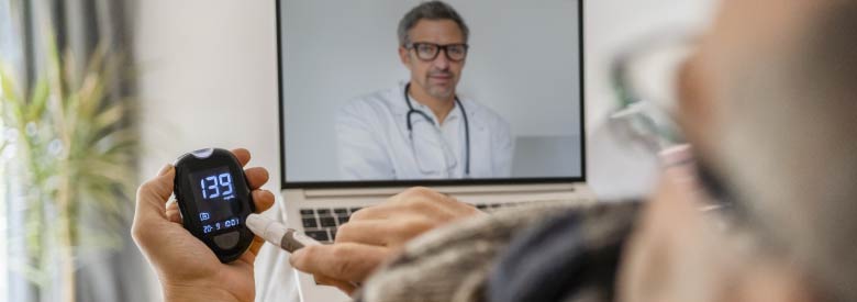 senior male on a video chat with a doctor while checking his blood pressure with a device