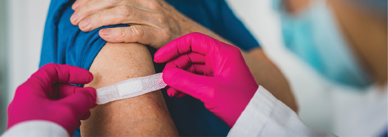 photo of a man receiving a covid-19 vaccine and then a bandage is being placed on his arm