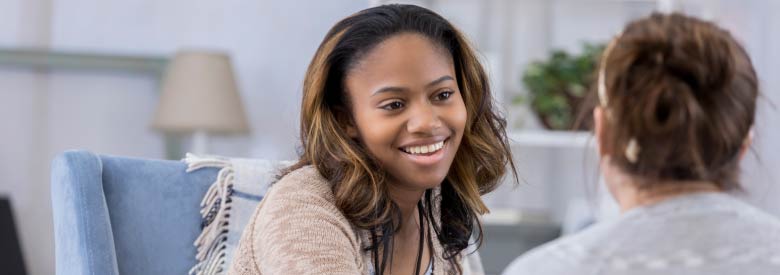 a young women smiling greeting another women