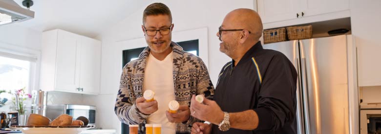 two men looking at their prescription bottles