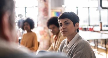 a women at a table talking to other people about mental health