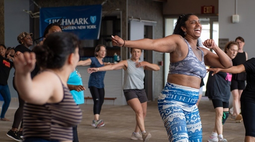 A group of adults are laughing and dancing together during a Highmark Northeastern New York sponsored fitness class.
