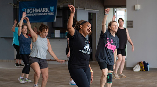 A group of adults are laughing and dancing together during a Highmark Northeastern New York sponsored fitness class.