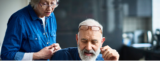 Older woman looking over the shoulder of an older man viewing an open laptop to show how the Highmark Medicare online quiz can quickly match you to a plan. 