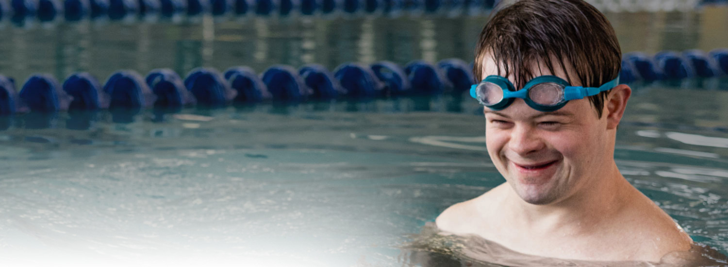 Young man in a pool with goggles pushed up on his head to show Highmark Blue Shield member services.