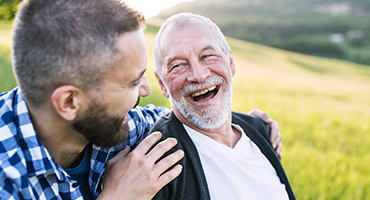 a man behind his father laughing while looking at each other