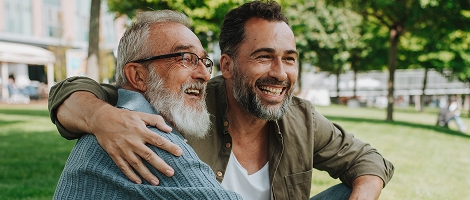 two men sitting together outside, laughing and enjoying their day knowing they have great Highmark insurance options