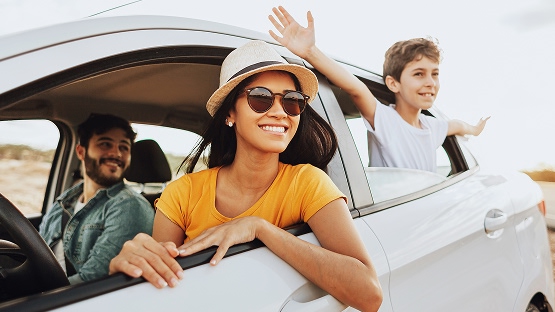 a family of three in a car, smiling and looking out their window knowing they have a great travel insurance benefit with Highmark