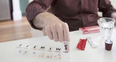 Close up of an older man organizing many prescription drugs sitting at white counter representing Highmark Medicare Plans.