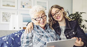 younger women embracing a senior women while looking at a digital tablet