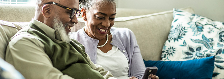 a couple on a couch looking at a smart phone