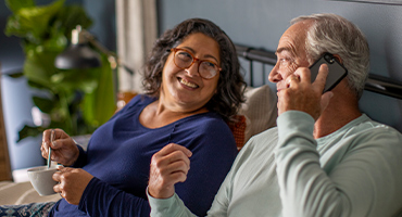 photo of a man and women on their couch talking on the phone