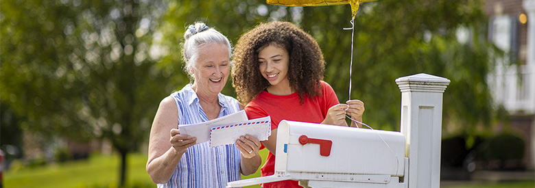 photo of two women at the mailbox reading their mail