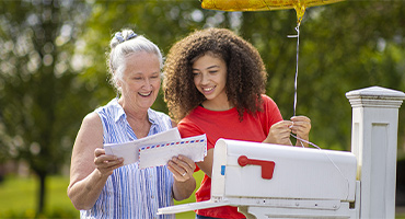 photo of two women at the mailbox reading their mail