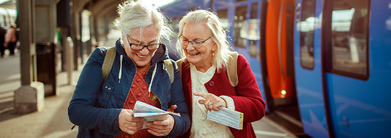 two senior women checking their boarding passes before entering the train