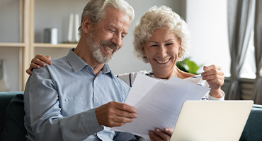 Retirement age man and women reading notes on paper about original medicare vs medicare advantage