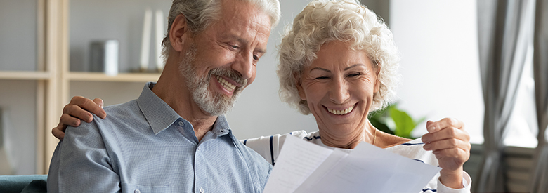 Retirement age man and women reading notes on paper about original medicare vs medicare advantage