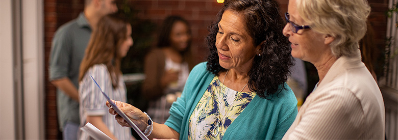 two senior women looking at a quarterly Medicare newsletter on PPO and HMO plans
