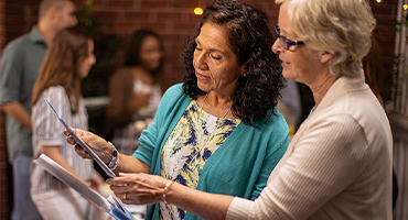 two senior women looking at a quarterly Medicare newsletter on PPO and HMO plans
