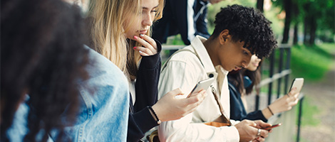 A group of young adults looking at their mobile devices to illustrate types of anxiety.