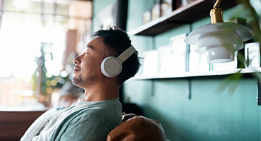 Young man listening to audio with headphones on to illustrate mental health disorders