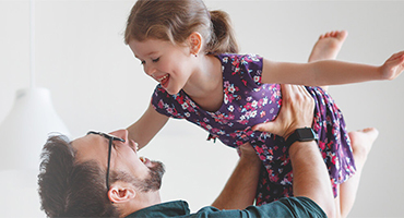 picture of a father holding his daughter in the air